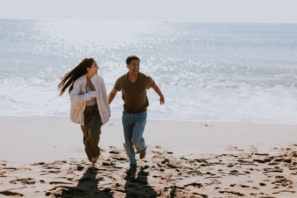 istock Joyful couple running hand in hand along a sunlit beach at sunset 2147511746