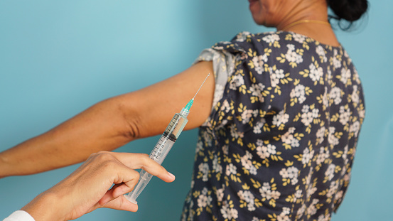 Medical professional administering a vaccination shot to an adult, emphasizing public health and prevention