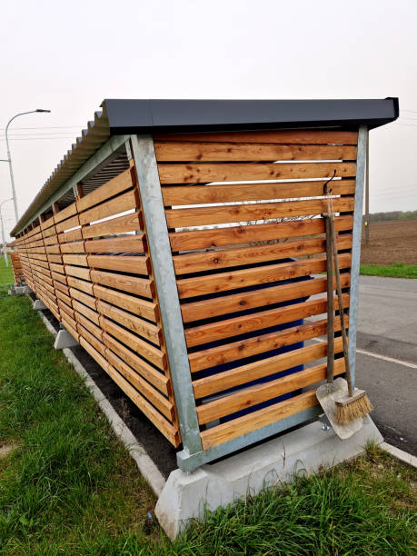 istock pergola roof with bus stop. combined with bin sorting. plastic, paper, glass separated into colored bins. wooden slats, blue sky, clouds, broom, trowel, sidewalk, street 2147512379