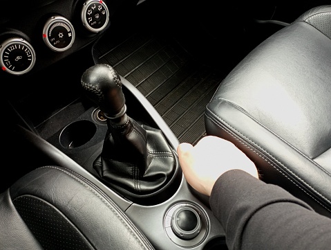 Gear shift knob in a car with a manual gearbox. Gearbox in a car. Man's hand near the gear knob.