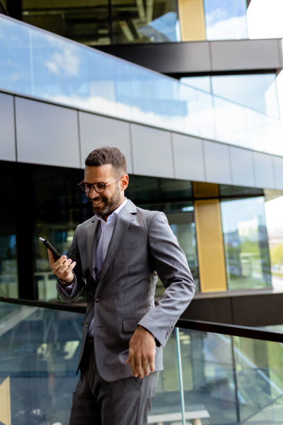 istock Confident Businessman Smiling in Sharp Suit Against Modern Glass Office Facade 2147512459