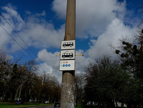 Bus and trolleybus stop signs with route numbers are on a concrete electric pole. The topic of urban transport and the timetable of buses and trams.