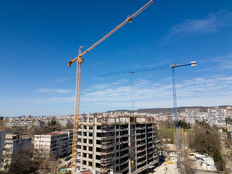 Construction site with multiple cranes in action, surrounded by various buildings in progress.