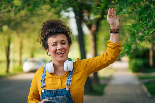 Portrait of a smiling woman standing on the street and waving to someone. Close up picture.