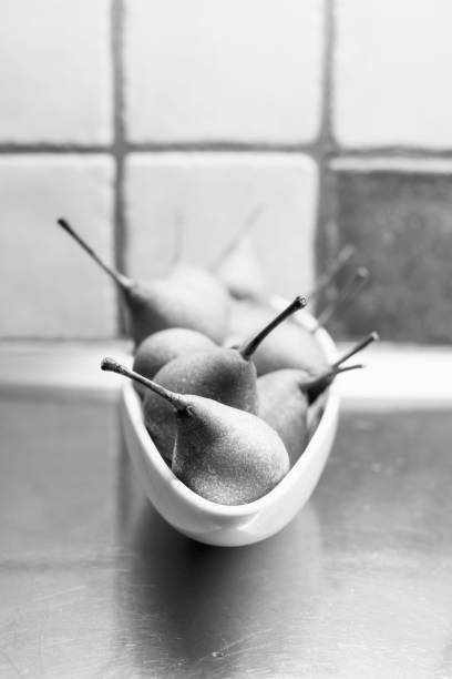 Black and white still life of pears in a oval bowl.
