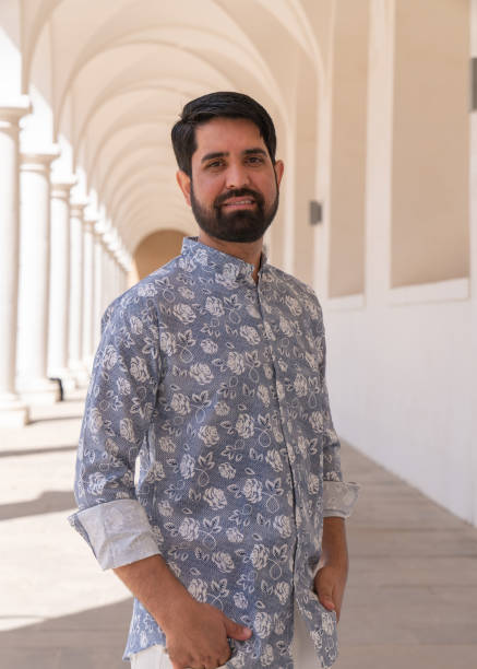 istock A modern, stylish Pakistani man with a dark beard and light clothes stands among white columns 2147516193