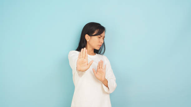 istock Asian woman with stop and no gesture on light blue background 2147516496