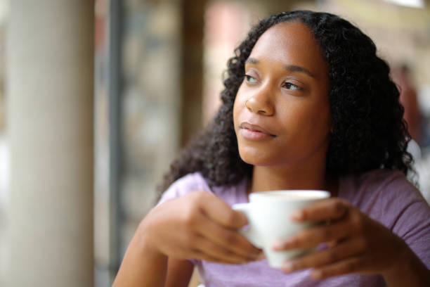 istock Black woman drinking coffee thinking looking at side 2147517120