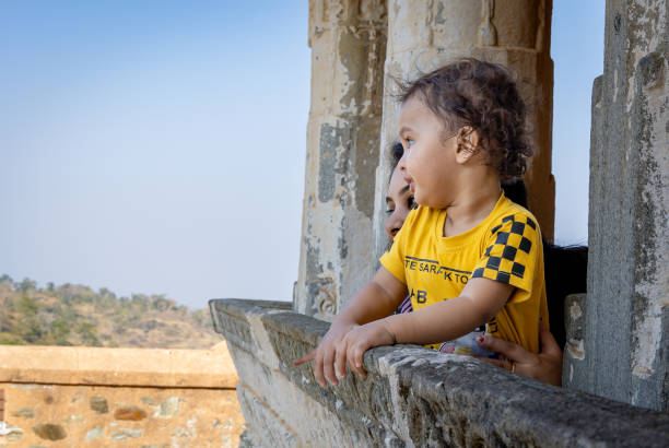 innocent kid with mother at window at morning from flat angle