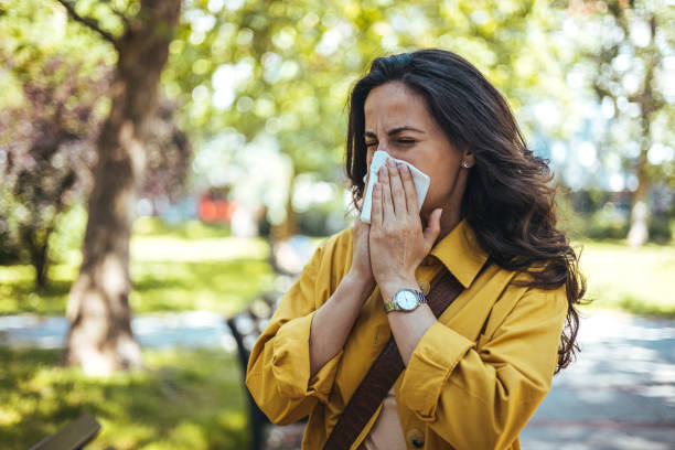 Portrait of unhealthy cute female in yellow top with napkin blowing nose Portrait of unhealthy cute female in yellow top with napkin blowing nose, looks to the source of the allergy, place for advertising. Rhinitis, cold, allergy concept. Pollen allergy symptoms season stock pictures, royalty-free photos & images