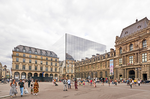 Paris, France - July 13, 2024: Reflection of pedestrians near the Louvre in the glass facade of the Architecture Jean Nouvel / chantier Fondation Cartier building.