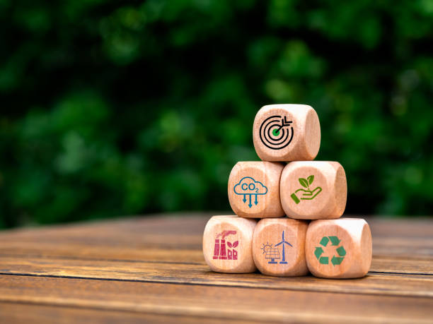 istock Environmental sustainability process, Carbon emissions reduction concept. Green target symbol on wooden cube block pyramid stack with renewable energy icons on table and forest background with space. 2147522746