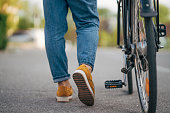 Image of female legs in yellow leggings and jeans. She pushes the bike.