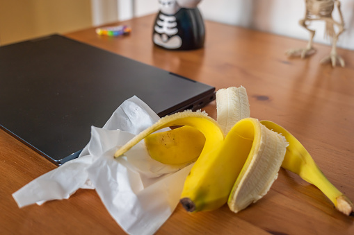 Fresh ripe banana fruit on table next to gaming laptop.