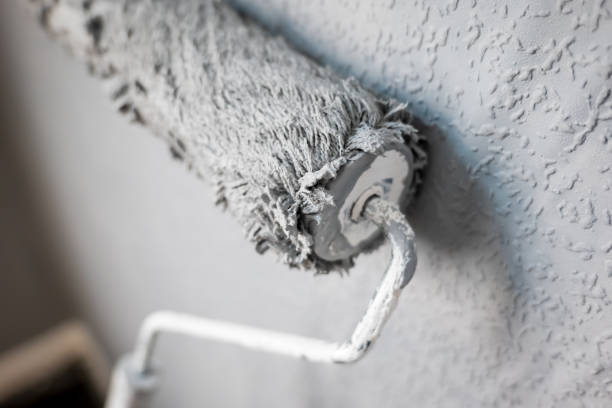 istock Paint roller extendable pole over painted woodchip wallpaper wall during home renovation in england uk 2147523078