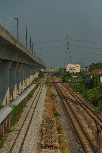 A train track with a bridge in the background. The train tracks are empty and the bridge is tall