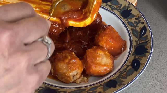 Pouring meatballs with sauce into plate