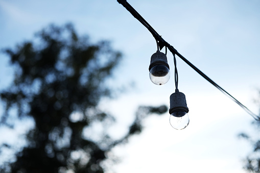 Equipped and electrical with light bulbs is shining and hanging in twilight of sunset before night