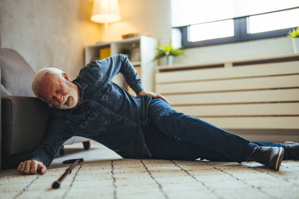 istock Sick senior old man falling down lying on the ground because stumbled at home alone with wooden walking stick in living room 2147527361