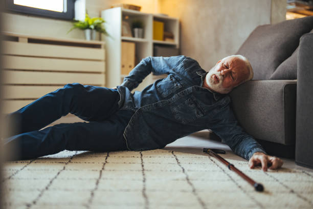 istock Sick senior old man falling down lying on the ground because stumbled at home alone with wooden walking stick in living room 2147527363