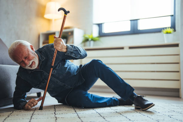 istock Sick senior old man falling down lying on the ground because stumbled at home alone with wooden walking stick in living room 2147527449