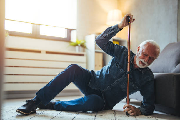 istock Sick senior old man falling down lying on the ground because stumbled at home alone with wooden walking stick in living room 2147527454