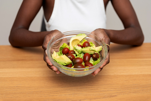 close up of African American Woman Holding Bowl with Fresh Salad. Healthy Eating Concept