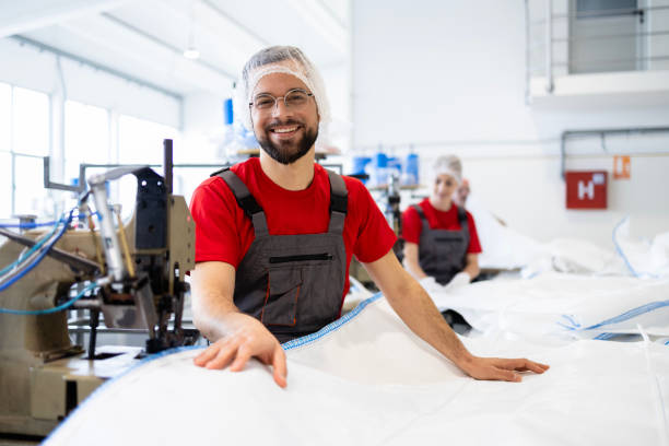 istock Portrait of professional tailor standing by sewing machine inside textile factory. 2147529383
