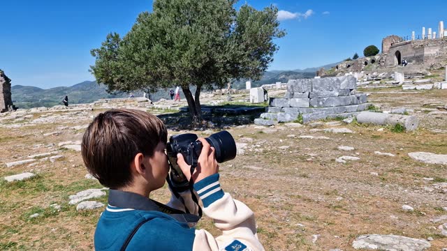 Little boy taking photos and videos with a professional camera in the ancient city