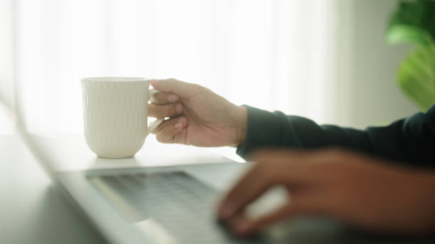 istock Asian man resting with tea or coffee while watching on laptop. 2147531817