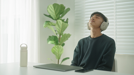 Young asian man taking a break from work at home.