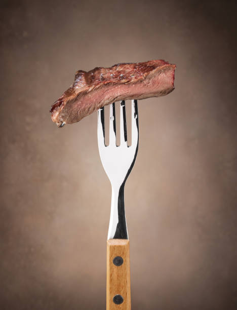 istock Pieces of steak on a fork on a dark background 2147532891