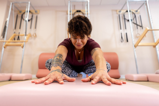 Full shot of a mid-adult woman stretching during a private Pilates group. She is concentrating, looking away from the camera wearing casual sportswear. The studio is located in Gateshead near Newcastle Upon Tyne.

Videos are available similar to this scenario.