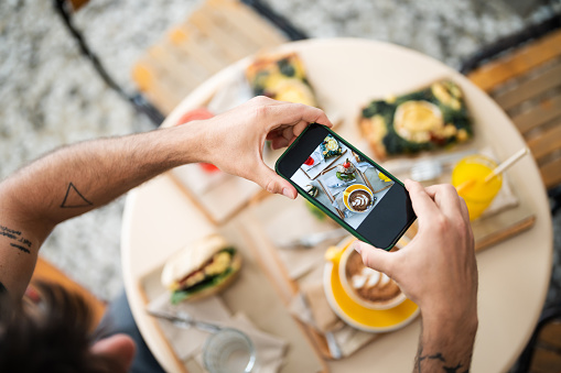 Hands holding smartphone taking photo of beautiful food