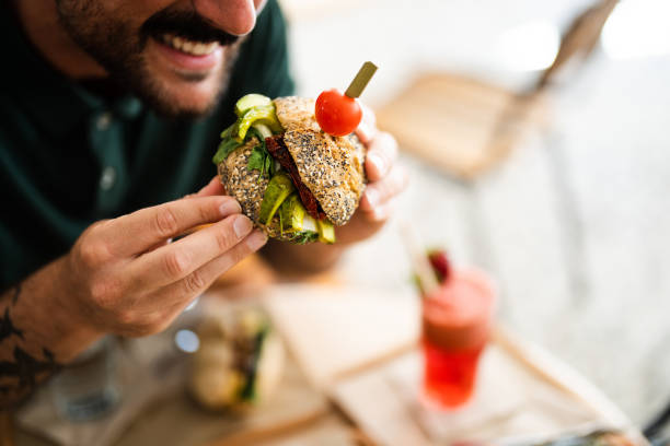 istock Young businessman during lunchtime holding sandwich while sitting in restaurant 2147535915