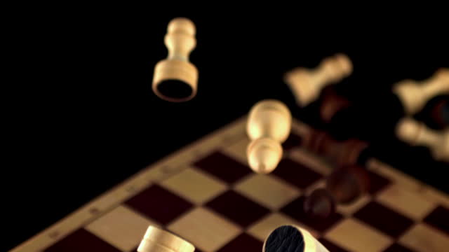 Chess pieces on wood board in darkness, surrounded by office equipment