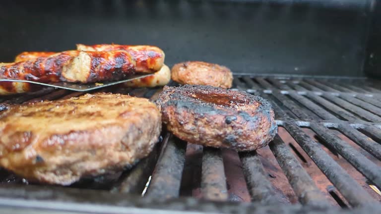 Smoky BBQ Beef Burger and Sausages Being Cooked and Flipped