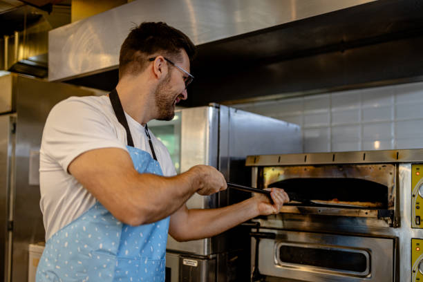 istock Baker placing pastries in oven 2147538050