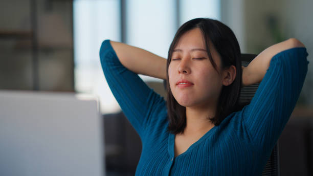 Freelancer businesswoman taking break from working and relaxing and doing breathing exercise in living room at home A freelancer businesswoman is taking a break from working and relaxing and doing breathing exercise in the living room at home. meditation room office stock pictures, royalty-free photos & images