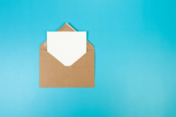 istock Top view of brown Kraft envelope, white card on blue background. 2147542845