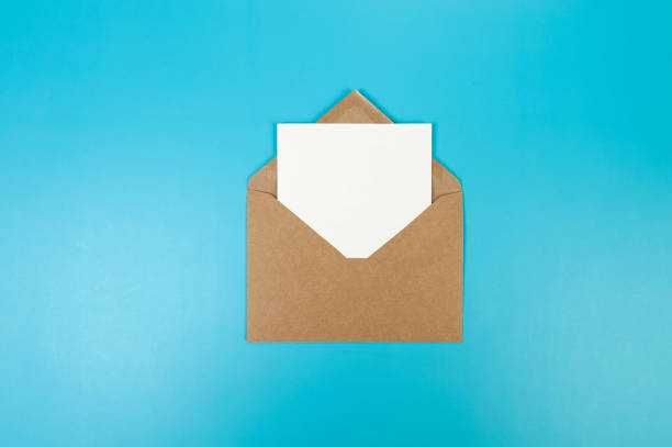 istock Top view of brown Kraft envelope, white card on blue background. 2147542846