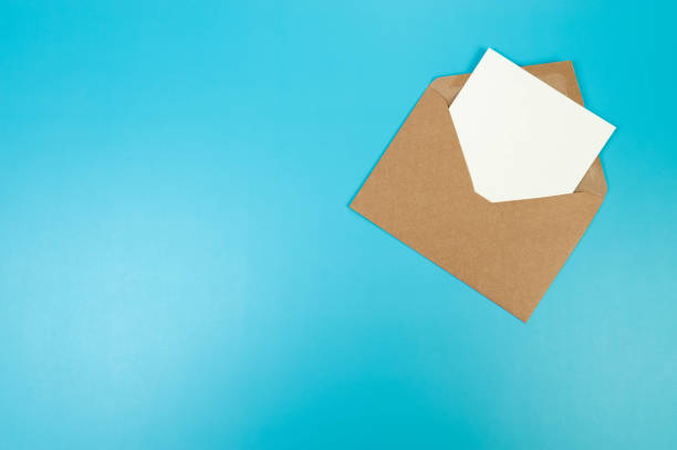 istock Top view of brown Kraft envelope, white card on blue background. 2147542849