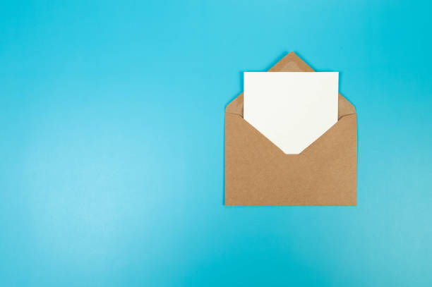 istock Top view of brown Kraft envelope, white card on blue background. 2147542854