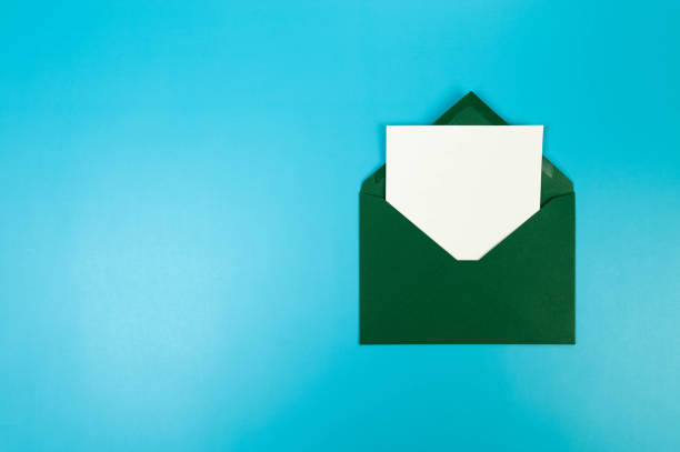 istock Top view of dark green envelope, white card on blue background. 2147542889