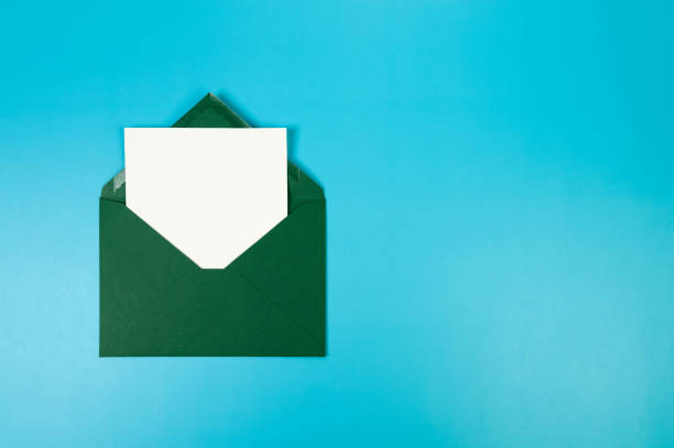 istock Top view of dark green envelope, white card on blue background. 2147542893