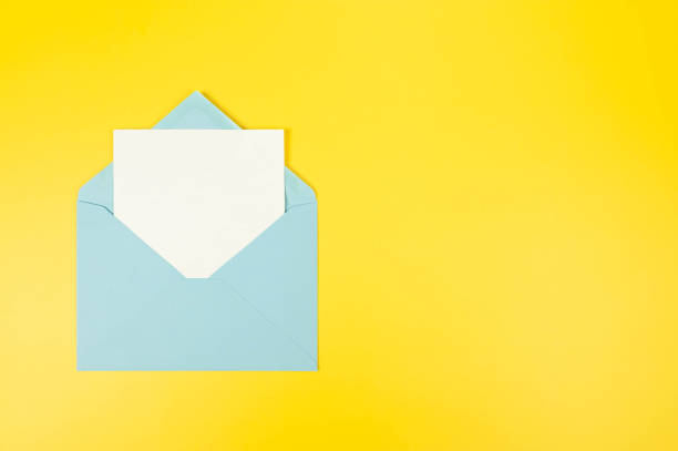 istock Top view of light blue envelope, white card on yellow background. 2147542909