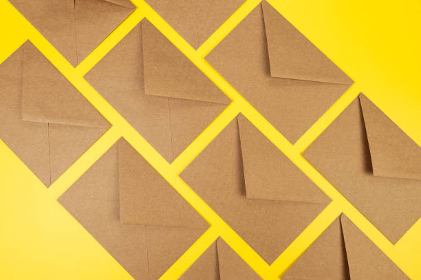 istock Top view of brown kraft envelopes on yellow background. 2147543018
