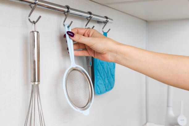 istock housewife removes kitchen strainer from hook on rail. 2147543109