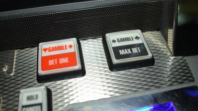 The player's hand presses buttons on a slot machine in a casino, close-up, slotmachine