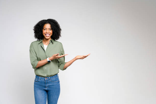 istock A dynamic African-American woman points with confidence, her joyful expression and casual business attire 2147543449